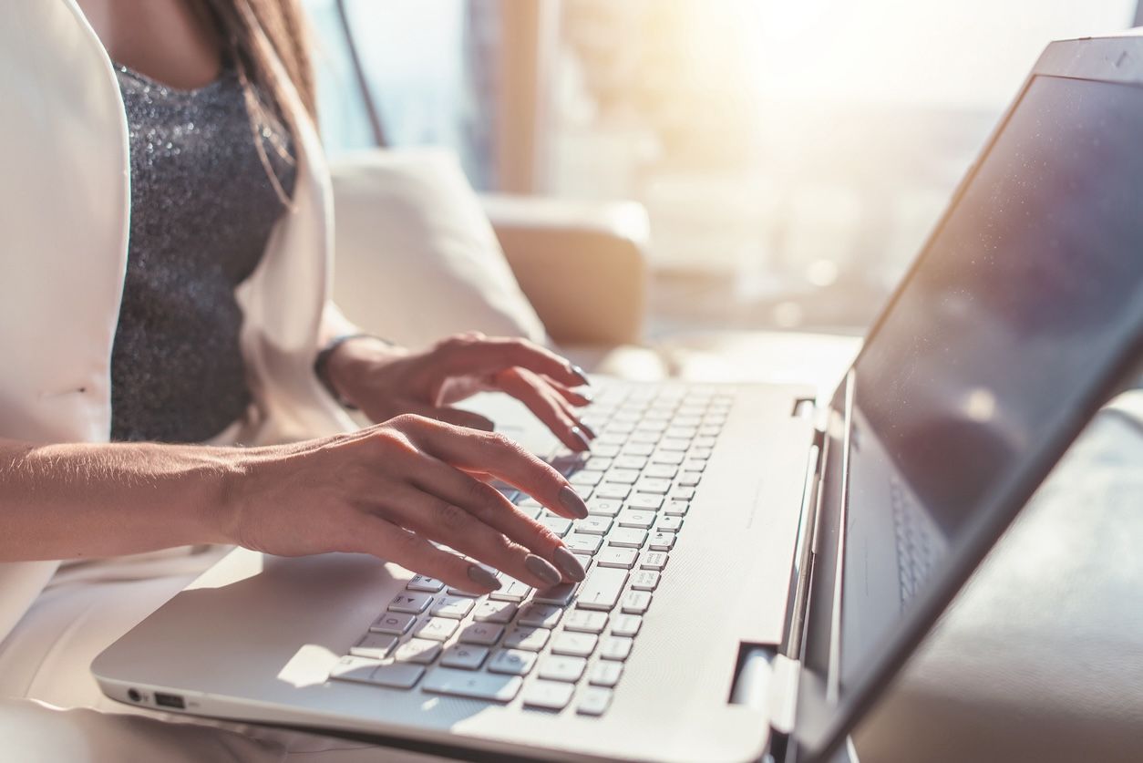 Woman typing on laptop while planning wedding and searching for venue tips online.