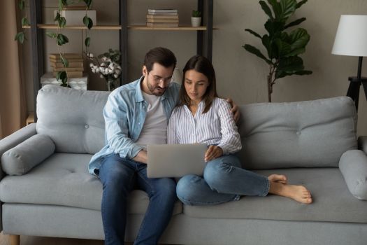 Engaged couple researching how to choose a wedding planner for their Tennessee wedding on a laptop at home.