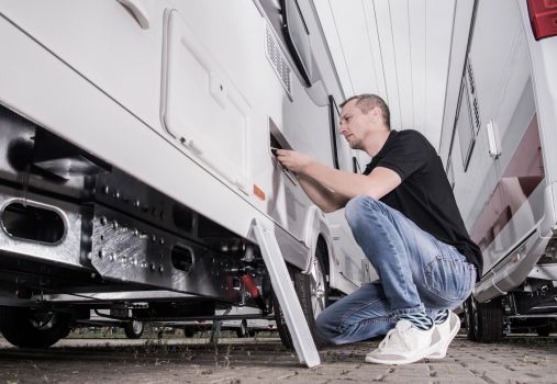 RV owner performing routine maintenance on a travel trailer as part of a seasonal RV maintenance schedule.