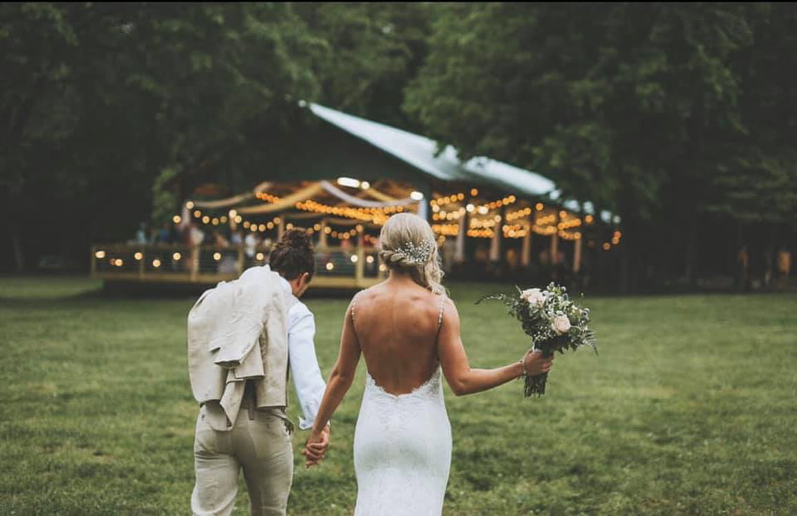 Newlywed couple walking hand in hand toward a beautifully lit outdoor pavilion at Rural Hill Farm in Mt. Juliet, Tennessee.