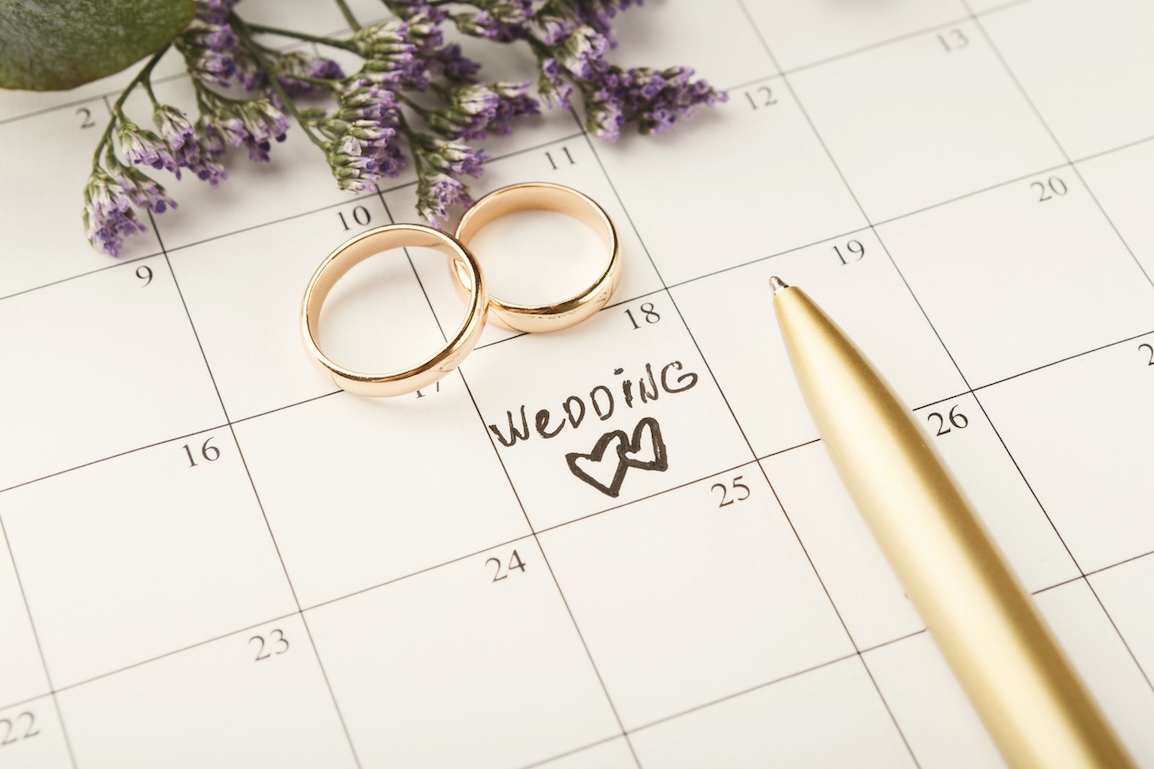Wedding written on calendar, with two wedding rings sitting beside it.