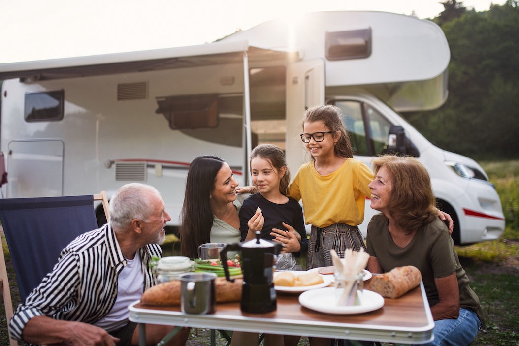 Family enjoying a meal at a picnic table beside their RV during a relaxing camping trip