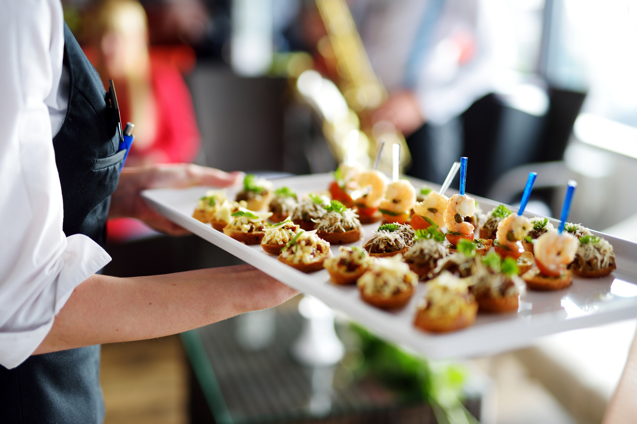 Server holding a tray of gourmet wedding appetizers at a reception, highlighting elegant catering presentation.