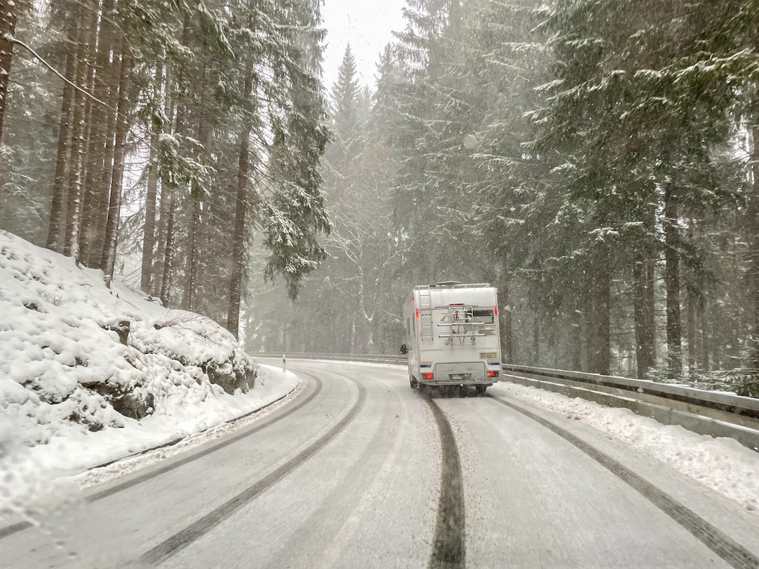 RV driving on a snowy road during winter weather for cold weather travel preparation