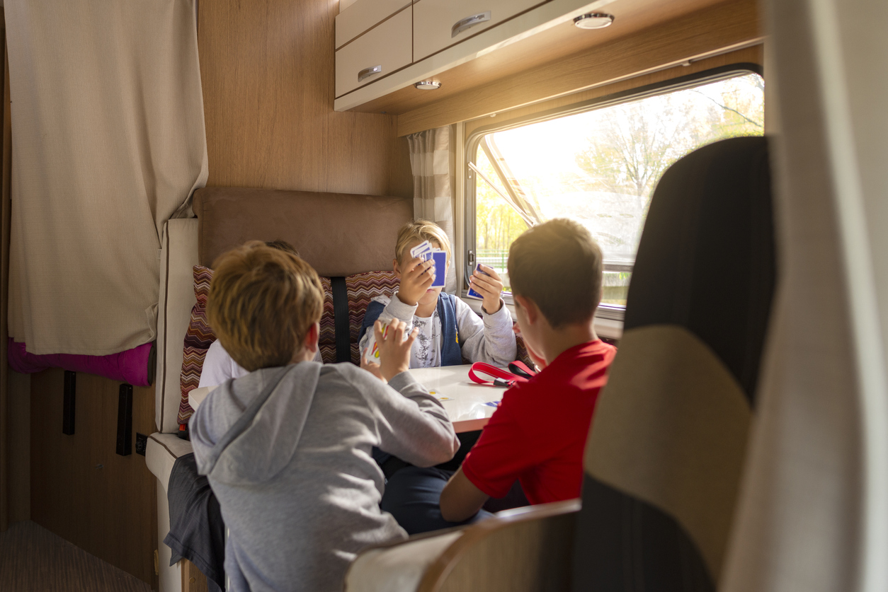 Children playing cards inside an RV during a family camping trip