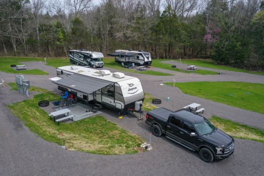 Full hookup RV sites at Rural Hill Farm near Nashville, featuring large campsites with picnic tables, firepits, and campers surrounded by trees and peaceful countryside.