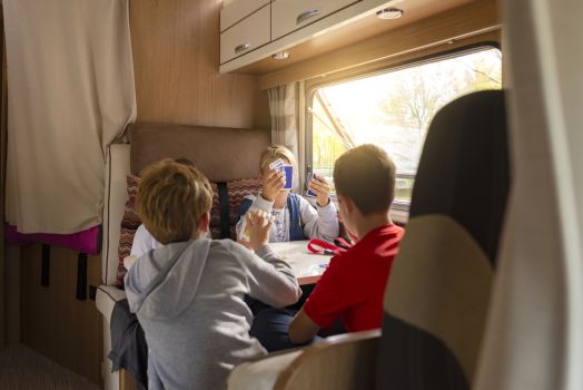 Children playing cards inside an RV during a family camping trip