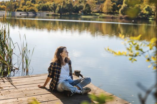 Woman relaxing by a scenic lake during fall RV camping near lake.