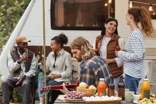 Friends enjoying RV camping together near Nashville, gathered around a table with food and drinks, relaxing outdoors by their camper.