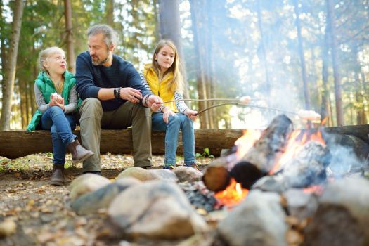 Sisters roasting marshmallows on the campfire with their dad.